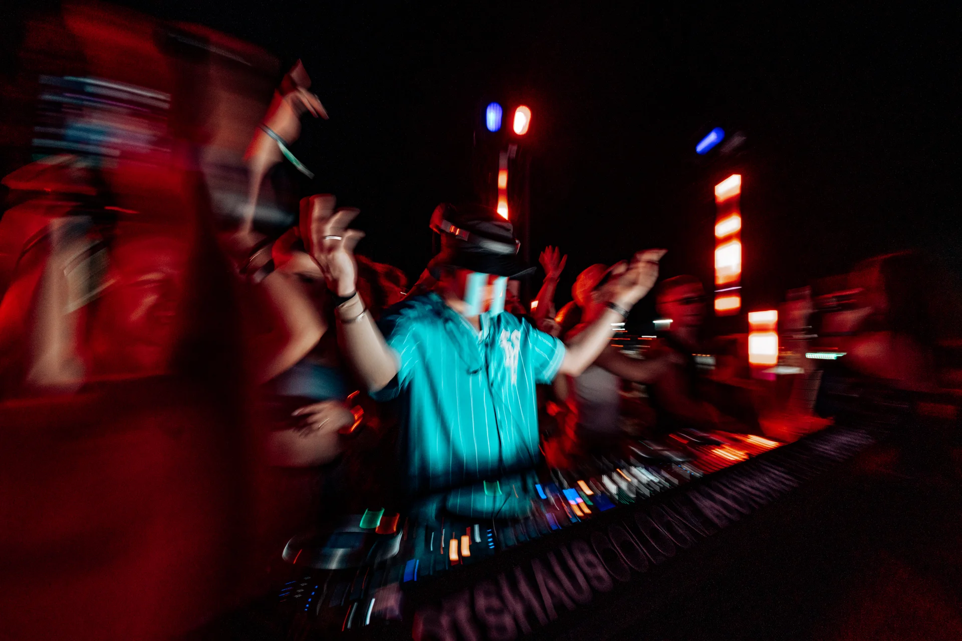 DHALI am DJ-Pult in Bewegung zwischen rotem Clublicht und feierndem Publikum