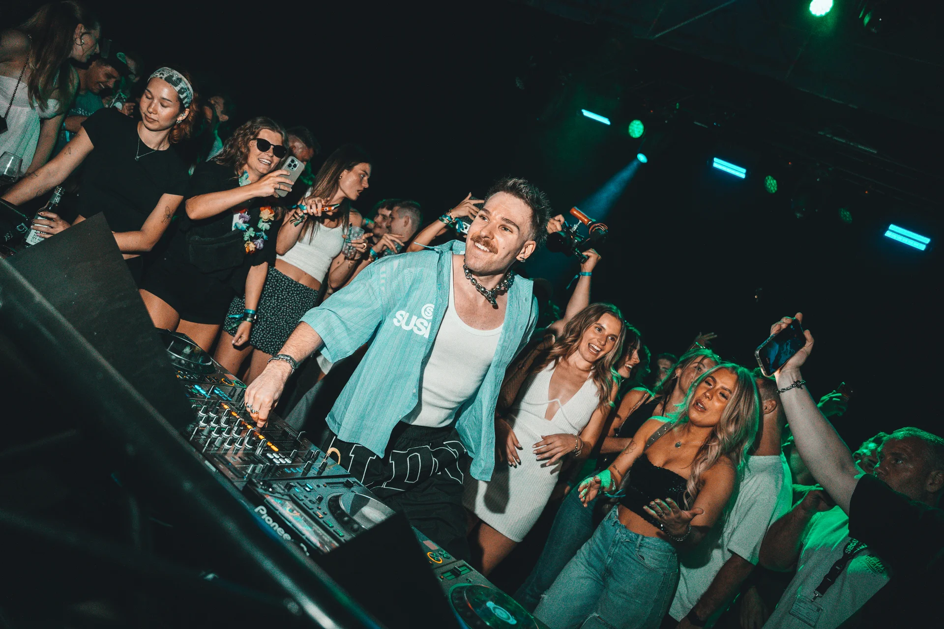 Ely Oaks lacht am DJ-Pult, umgeben von Publikum
