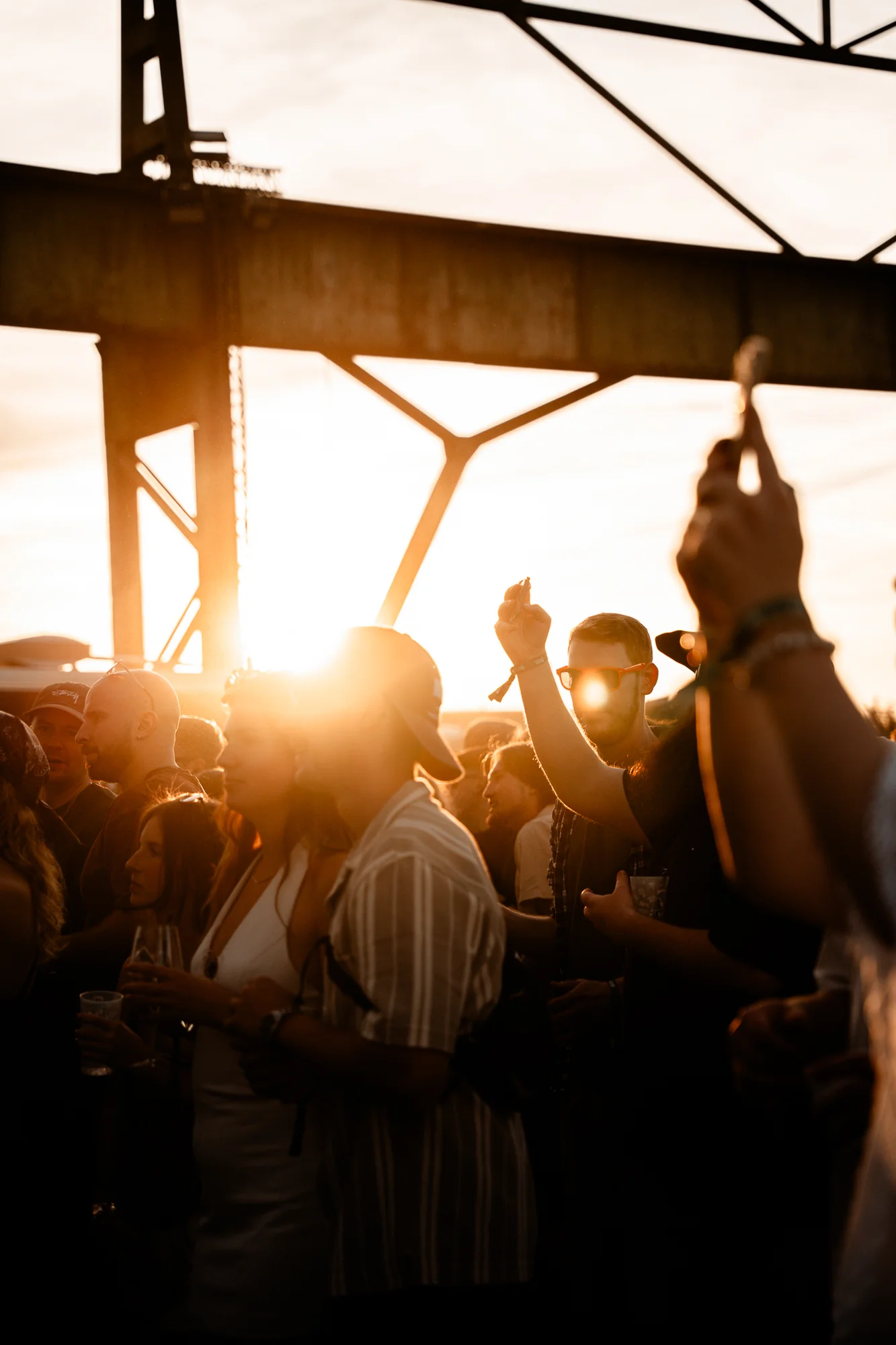 Feiernde Festivalgäste im goldenen Sonnenuntergang unter dem Hallendach