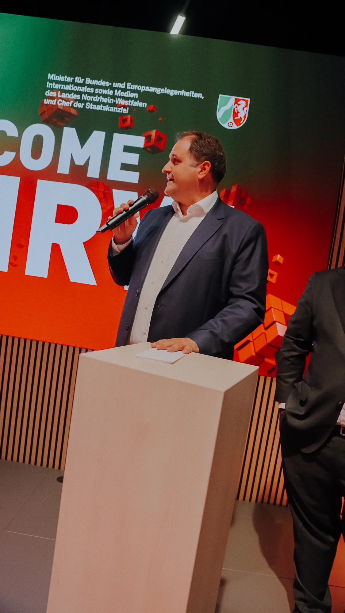 Begrüßung mit Mikrofon vor der Welcome-to-NRW-Bühne