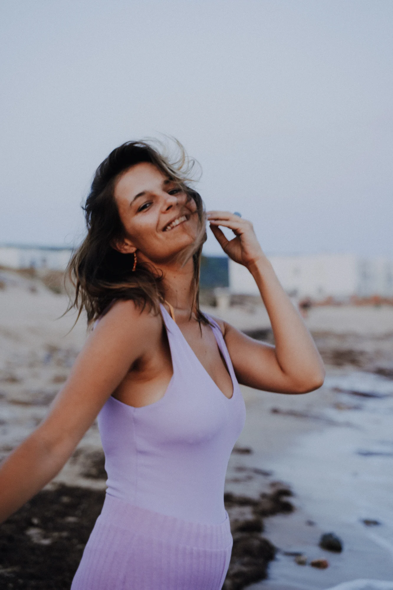 Lachende Person im lilafarbenen Kleid am Meer