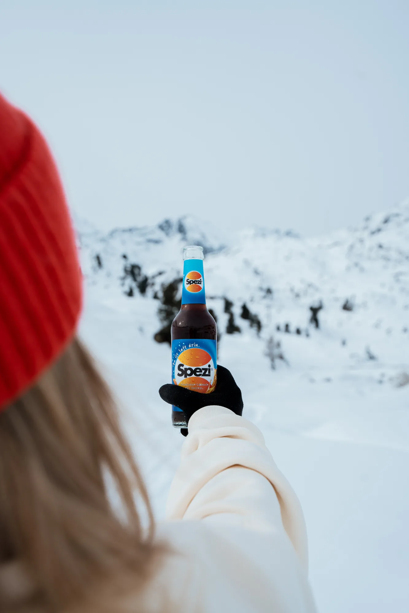 Spezi-Flasche vor einer verschneiten Berglandschaft