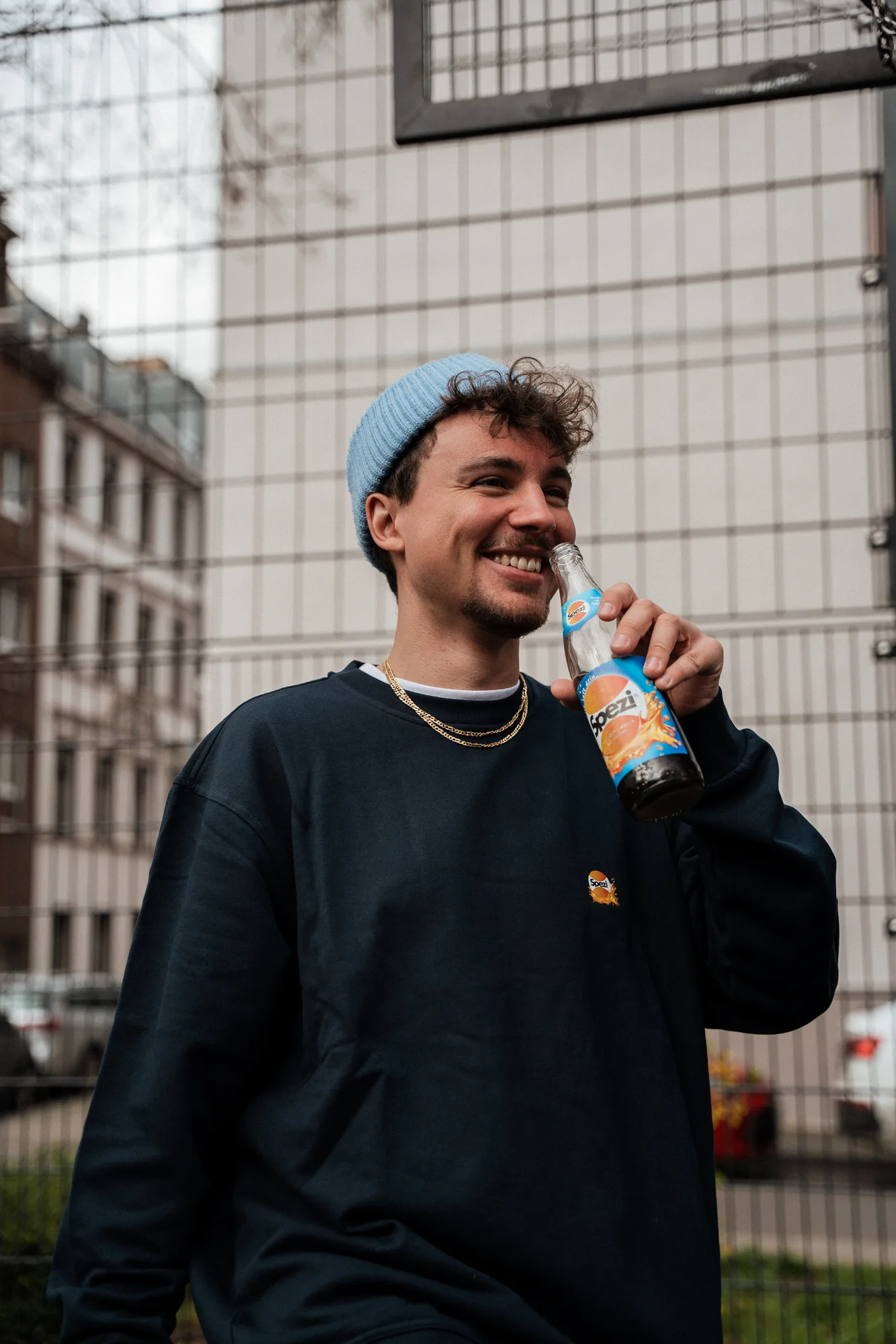 Lifestyleporträt mit Spezi-Flasche und dunkelblauem Spezi-Merch-Pulli