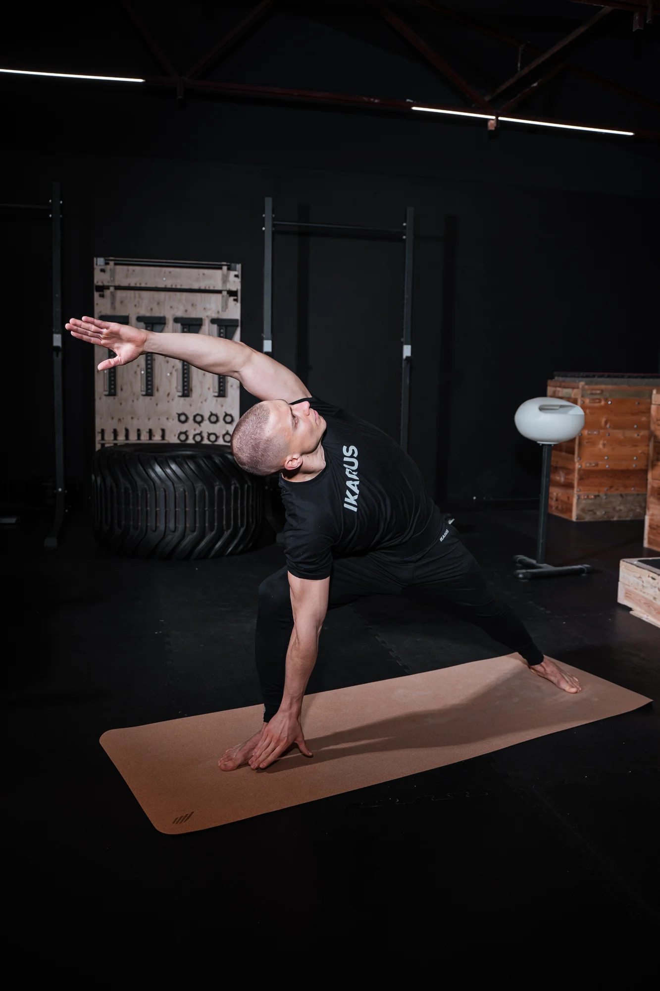 Athlet bei einer seitlichen Dehnung auf der Matte im dunklen Trainingsstudio
