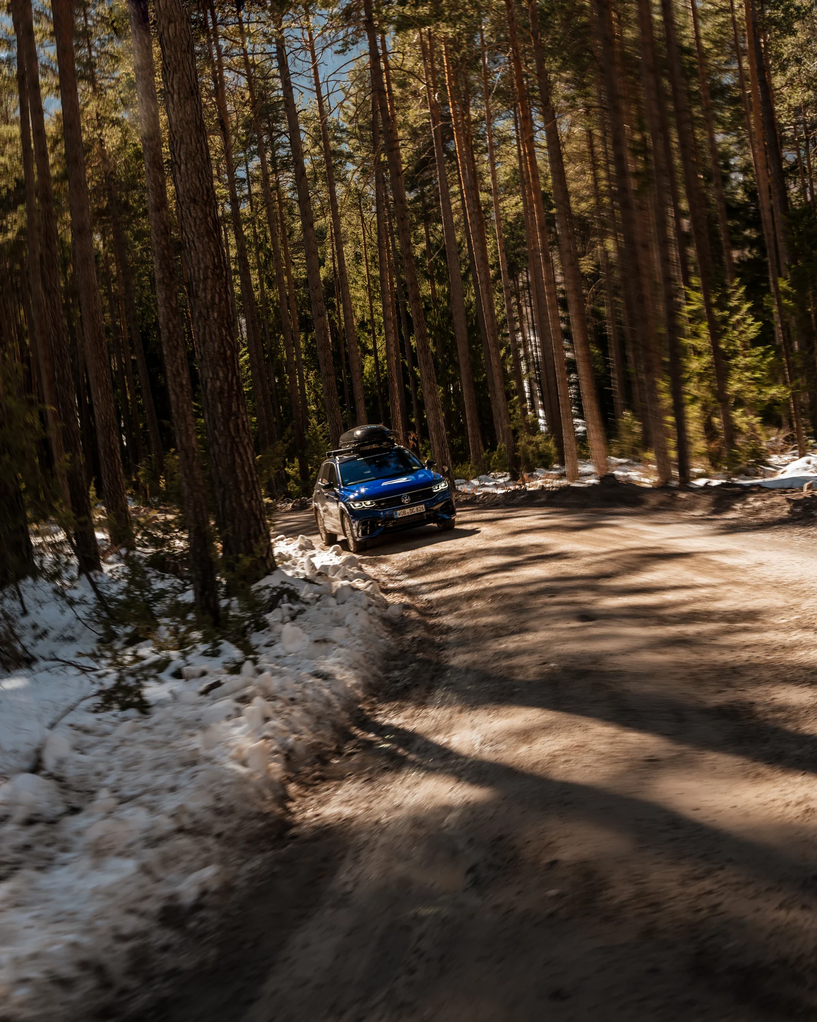 Blauer Volkswagen auf einer verschneiten Waldstraße